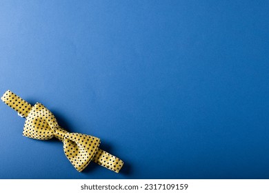 Overhead view of yellow bowtie with polka dots isolated over blue background, copy space. Menswear, fashion and elegance concept. - Powered by Shutterstock