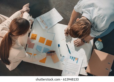Overhead view of young business people sitting on floor and working with charts 