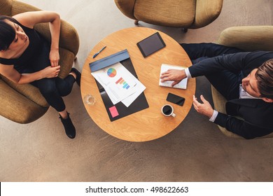 Overhead View Of Young Businessman And Woman Meeting In Office Lobby. Coworkers Discussing New Business Project.