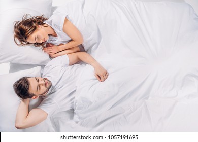 Overhead View Of Young Couple Sleeping In Bed Together