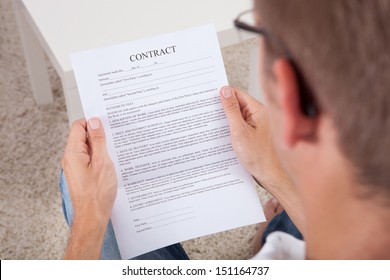 Overhead View Of Young Man Reading A Contract Document