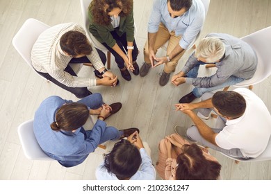 Overhead View Of Young And Mature Patients Meeting For Conversation With Psychologist Or Psychotherapist. High Angle Shot Of Group Of People Sitting In Circle During Therapy Session With Psychiatrist