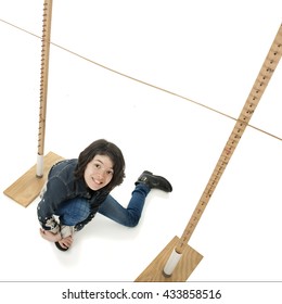 An Overhead View Of A Young Teen Girl Who Has Fallen Under A Limbo Stick.  On A White Background.