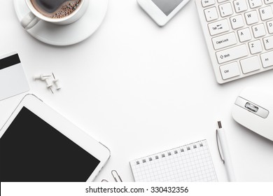 Overhead Of White Office Table With Notebook, Computer Keyboard And Mouse, Tablet Pc And Smartphone. Copy Space