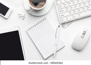 Overhead Of White Office Table With Notebook, Computer Keyboard And Mouse, Tablet Pc And Smartphone