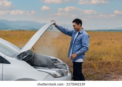 Overheated car and engine broke with breakdown radiator steam and hot oil smoke from under the hood. Asian young man auto driver standing open car hood on outdoors. Automobile motor problem concept.