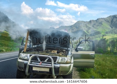 overheated car in the field, bright sunlight, steam under the hood. smoking engine in SUV car. Smoke coming out from overheat engine. Waiting car tow service. Mountain Altai, Russia