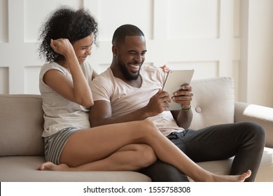 Overjoyed african American couple relax on couch playing game on tablet together, excited mixed race ethnicity husband and wife using pad happy with online win, feel euphoric reading good news - Powered by Shutterstock