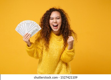 Overjoyed African American Girl In Fur Sweater Posing Isolated On Yellow Background. People Lifestyle Concept. Mock Up Copy Space. Holding Fan Of Cash Money In Dollar Banknotes, Doing Winner Gesture