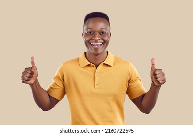 Overjoyed African American Man Customer Isolated On Brown Studio Background Show Thumbs Up Give Recommendation. Smiling Biracial Male Client Laugh Recommend Good Quality Service.