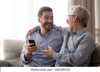 Overjoyed Aged Father Embraces Grown Up Child Men Feels Happy Received Great Medical Insurance Offer By Sms Mobile Phone, Read Anecdotes Laughing, Warm Relations, Connection Dad And Adult Son Concept