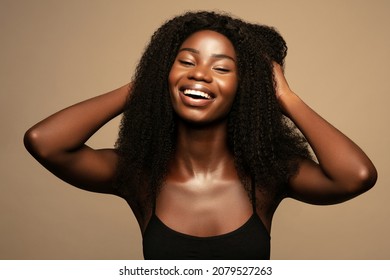 Overjoyed. Beauty fashion portrait of happy young beautiful african american woman with volume,curly hair against beige background 