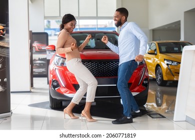 Overjoyed Black Couple Celebrating Buying New Car, Dancing In Dealership Office. Happy African American Spouses Having Fun In Auto Salon, Emotionally Reacting To Automobile Purchase, Free Space