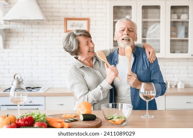 Overjoyed caucasian senior family spouses couple grandparents singing and dancing, hugging while cooking at home kitchen. Quality time and acts of service - love language - Powered by Shutterstock