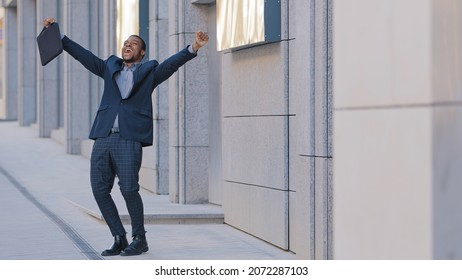 Overjoyed confident African businessman winner walk alone outdoors feel overjoyed excited jumping dancing celebrating professional triumph victory success, corporate reward or career promotion concept - Shutterstock ID 2072287103
