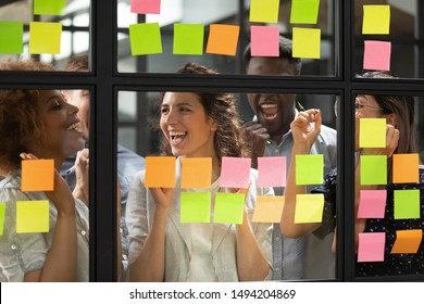 Overjoyed Diverse Business Team People Stand Behind Glass Wall With Sticky Notes Celebrate Corporate Success Win Victory, Finished Project Job Well Done Feel Happy About Good Work Results Concept