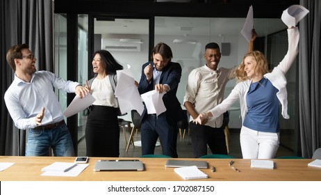 Overjoyed diverse businesspeople have fun in boardroom celebrate successful project together, happy excited multiracial colleagues dance laugh with paperwork in office, Friday celebration concept - Powered by Shutterstock