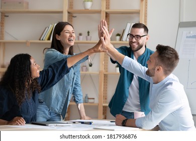 Overjoyed Diverse Employees Giving High Five At Corporate Meeting, Excited Colleagues Joining Hands, Celebrating Business Achievement, Good Teamwork Results, Engaged In Team Building Activity