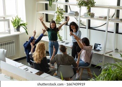 Overjoyed diverse multiethnic businesspeople have fun celebrate shared group achievement in office, excited multiracial colleagues engaged in teambuilding activity, motivated for results at briefing