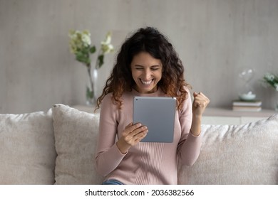 Overjoyed emotional young latina woman looking at digital tablet screen, celebrating online lottery auction betting giveaway win, feeling excited reading email with amazing news, internet success. - Shutterstock ID 2036382566