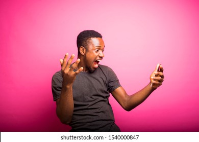 Overjoyed Excited Back African Man Glad To Recieve Text Message Informing About Salary, Rejoices Good News, Stares At Mobile Phone, Gestures Actively From Happiness, Standing  Alone. Reaction Concept
