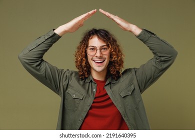 Overjoyed Exultant Excited Fancy Long Curly Hair Young Brunet Man 20s Wears Khaki Shirt Hold Folded Hands Above Head Like House Roof Stay Home Isolated On Plain Olive Green Background Studio Portrait