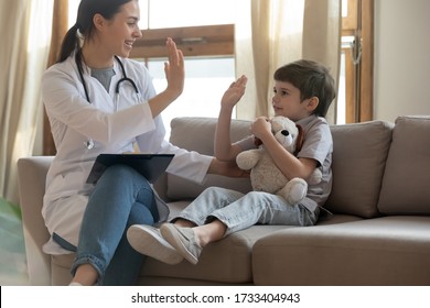 Overjoyed Female Nurse Or Doctor Have Fun Give High Five Cheer Little Boy Patient At Consultation In Hospital, Smiling Woman Pediatrician Greeting With Small Child Client, Children Healthcare Concept