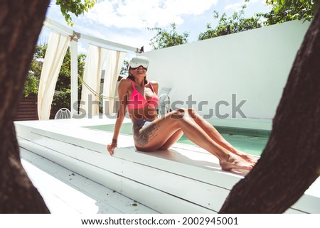 Overjoyed fit tanned woman in virtual reality glasses outdoor by swimming pool at hot beautiful summer day