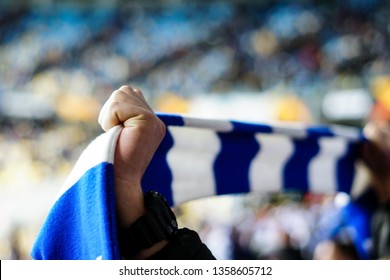 Overjoyed Football Fan Holding A Scarf And Cheering