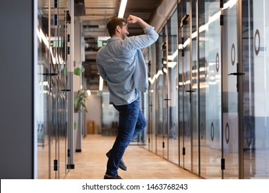 Overjoyed funny young business man jumping in hallway celebrate success victory win reward, happy excited male employee rejoice promotion work well done on friday yes gesture dancing alone in office
