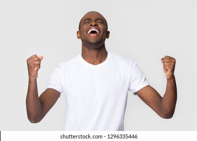 Overjoyed happy young african american man triumphant celebrating lottery betting win screaming with joy isolated on white blank studio background, excited black guy winner rejoicing success victory