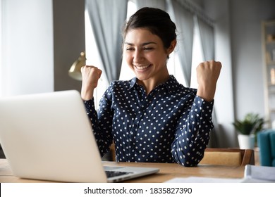 Overjoyed indian ethnicity girl sit at desk looks at laptop screen read incredible news clench fists makes yes gesture celebrate on-line lottery gambling win, getting new job offer feels happy concept - Shutterstock ID 1835827390