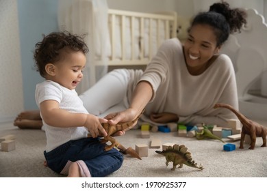 Overjoyed loving young African American mother play with toys block with small baby daughter. Happy smiling ethnic mom have fun feel playful with little toddler kid child. Parenthood concept.