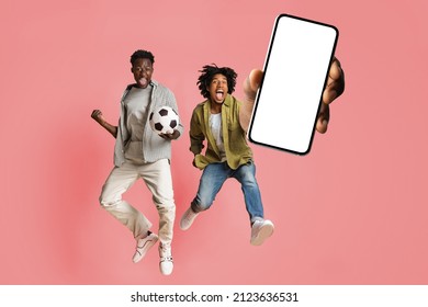 Overjoyed male friends jumping and showing big smartphone with empty white screen, excited black guys celebrating win, pink studio background, mock up collage banner - Shutterstock ID 2123636531