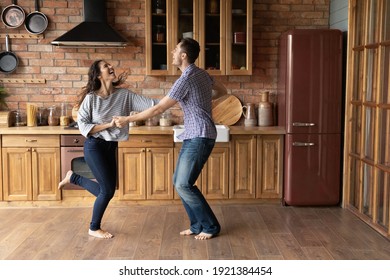 Overjoyed Man And Woman Holding Hands, Dancing In Modern Kitchen, Satisfied Young Couple Excited By Relocation, New Own Apartment, Mortgage, Family Enjoying Leisure Time Together, Having Fun