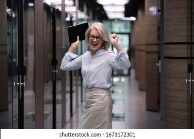 Overjoyed middle-aged businesswoman stand dance in modern company office corridor, happy senior female boss or employee feel excited celebrate successful project or have Friday fun, success concept - Powered by Shutterstock