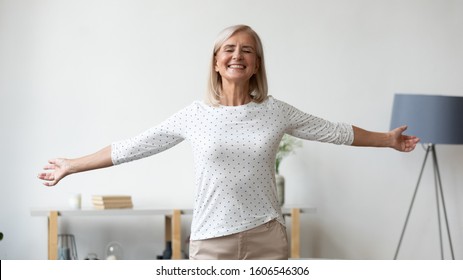 Overjoyed Middle-aged Grandmother Female Pensioner Stretch Hands Have Fun Dance In Living Room At Home, Happy Positive Mature Woman Relax Feel Excited Joyful With New Day, Enjoy Good Healthy Life