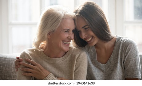 Overjoyed millennial Caucasian woman embrace happy older 60s mom enjoy family weekend reunion together. Smiling mature mother and adult grownup daughter hug laugh sharing secrets at home. - Powered by Shutterstock