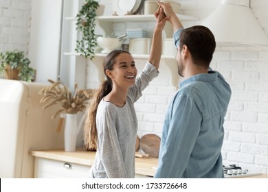 Overjoyed Millennial Husband And Wife Dancing In Modern Kitchen Celebrate Wedding Anniversary At Home Together, Happy Young Couple Tenants Have Fun Enjoy Family Weekend In New Own House Or Apartment