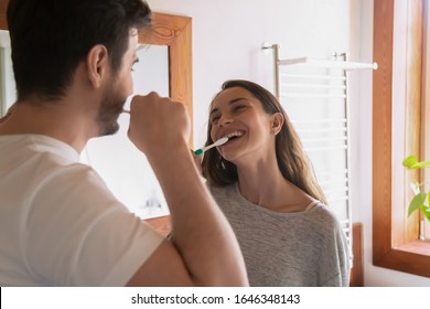 Overjoyed millennial loving couple enjoy daily morning routine in new renovated design bathroom, happy young husband and wife have fun brush clean teeth in bath together, oral hygiene concept - Powered by Shutterstock