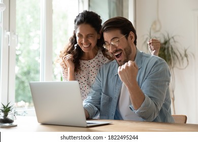 Overjoyed Millennial Man And Woman Triumph Win Online Lottery On Laptop. Happy Excited Young Caucasian Couple Feel Euphoric With Good Email, Get Amazing Sale Offer Or Discount Deal On Computer.