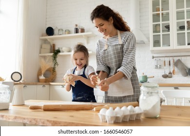 Overjoyed millennial mom have fun baking cookies or pastries with cute little preschooler girl at home, happy young mother teach cook together with small daughter doing bakery in modern kitchen - Powered by Shutterstock