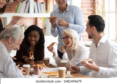 Overjoyed Multiracial Employee Have Fun Eating Pizza Drinking Coffee In Office Together, Smiling Happy Diverse Colleagues Having Lunch Break Laughing Enjoying Italian Fast Food Takeaway Delivery