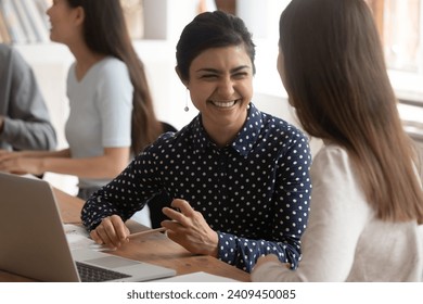 Overjoyed multiracial millennial female students sit at desk in classroom laugh working on educational project together, smiling multiethnic girls have fun joke brainstorming cooperating at lesson - Powered by Shutterstock