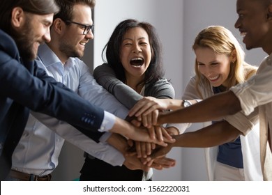 Overjoyed Older Asian Businesswoman Joining Hands With Young Multiracial Coworkers, Sharing Corporate Success. Laughing Korean Mature Female Team Leader Engaging Employees In Teambuilding Activity.