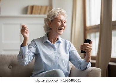 Overjoyed Older Woman Looking At Mobile Phone Screen, Excited By Receiving Good News. Happy Mature Granny Celebrating Online Lottery Win Notification, Getting Reward, Low Sale Price On Goods.