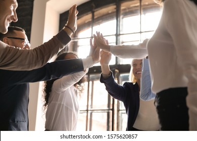 Overjoyed older and younger teammates joining hands in air, giving high five, celebrating shared company success in business meeting. Happy diverse colleagues coming to common decision, showing unity. - Shutterstock ID 1575620857