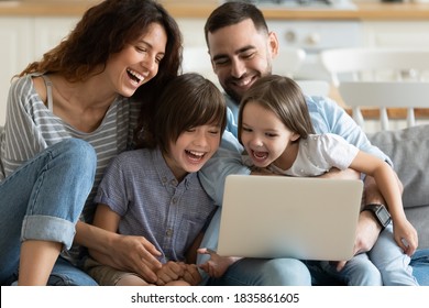 Overjoyed parents with little son and daughter using laptop together, looking at screen, sitting on cozy couch at home, happy mother and father with two kids making video call, having fun with device - Powered by Shutterstock