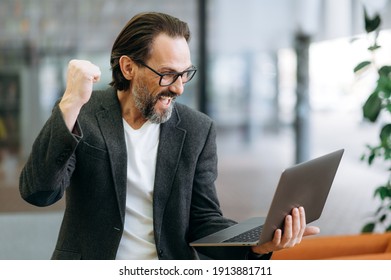 Overjoyed Senior Adult Businessman Is Using Laptop, Receive Good News. Excited Mature Entrepreneur Got Promotion On Work Or Have Done Successful Project, Enjoy Own Results