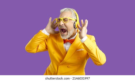 Overjoyed Senior Eccentric Man In Suit And Glasses Scream Sing Listen To Music In Wireless Headphones. Funny Old Male Have Fun Enjoy Good Quality Sound In Modern Earphones. Technology Concept.